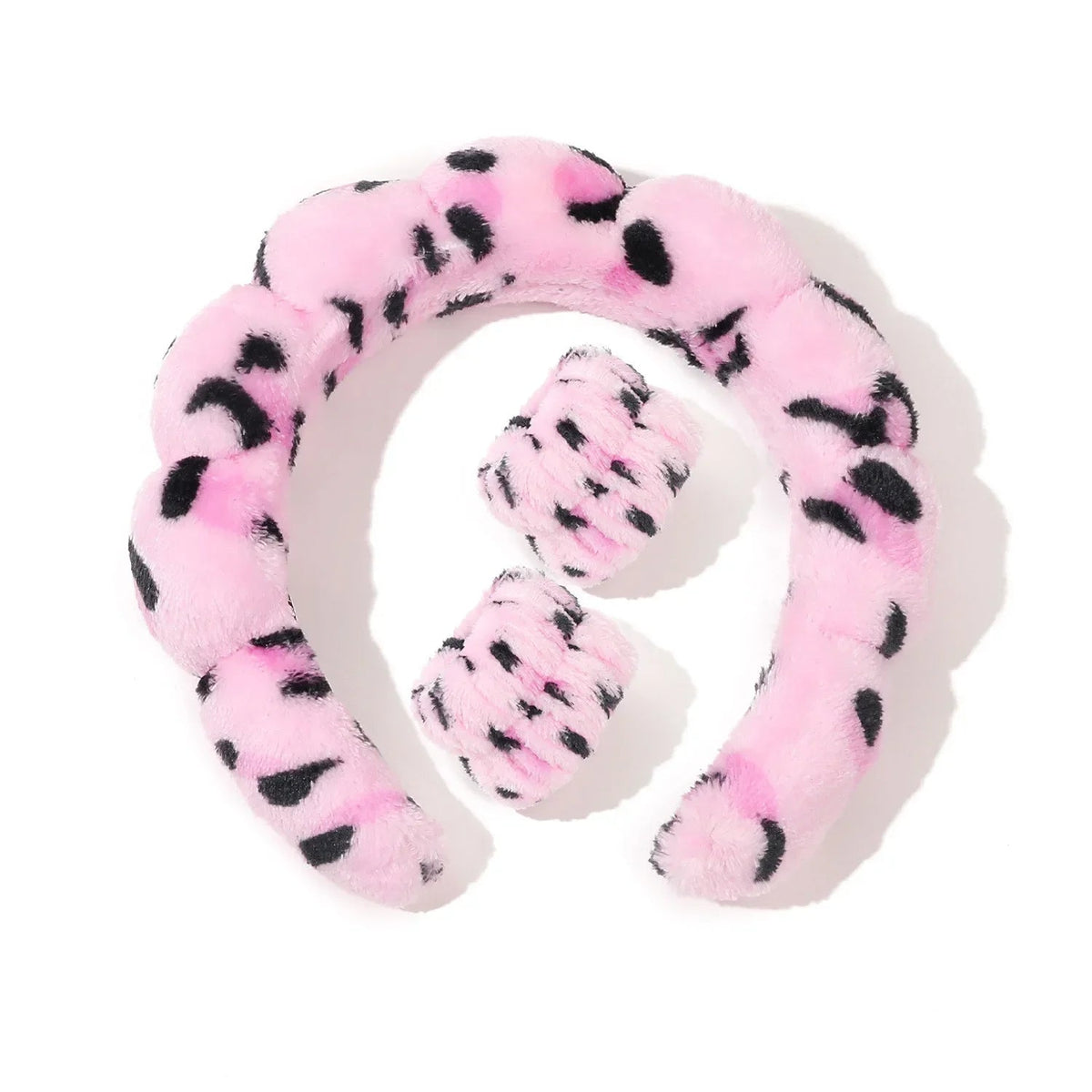 Pink plush headband with black polka dots on a white background